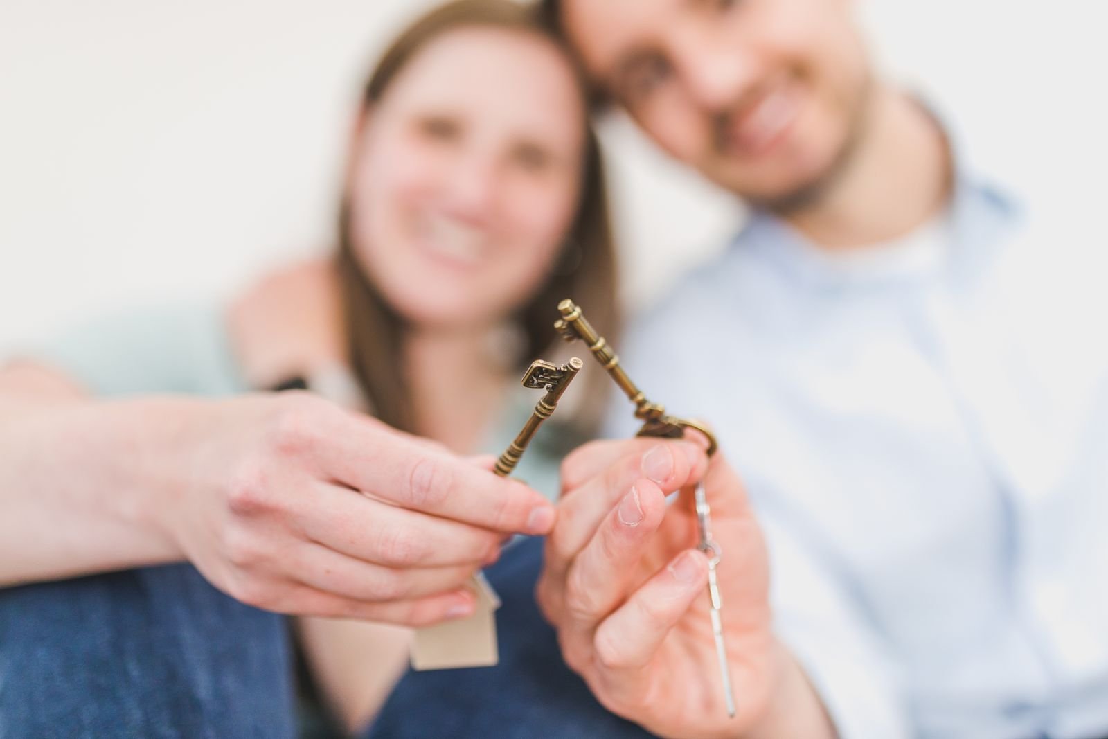 Pareja joven sonriente sujetando juntas las llaves de su nueva vivienda
