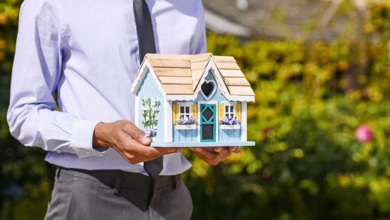 Persona sosteniendo una casa en miniatura, representando el seguro de vida y hogar vinculado a la hipoteca